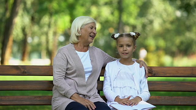 漂亮的老奶奶抱着小孙女听她讲故事，女性八卦视频素材