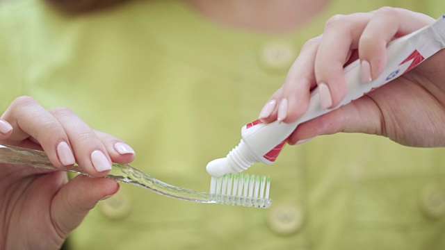 靠近女人的手挤牙膏在牙刷上。口腔卫生的概念视频素材