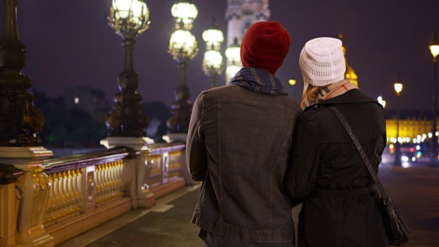 快乐的夫妇在Pont Alexandre III桥在晚上的后视图视频素材