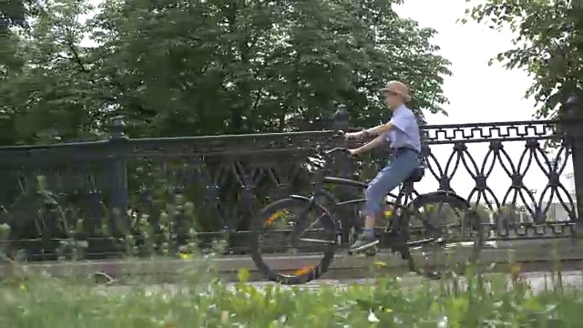 戴着帽子的快乐男孩在城市公园里骑自行车，在户外视频素材