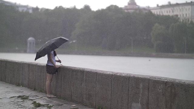 孤独的女孩撑着伞走在雨天的街道上，慢镜头视频素材