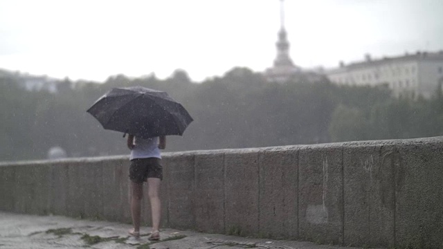 孤独的女孩撑着伞走在雨天的街道上，慢镜头视频素材