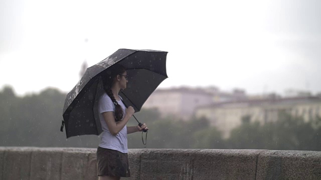 孤独的女孩撑着伞走在雨天的街道上，慢镜头视频素材