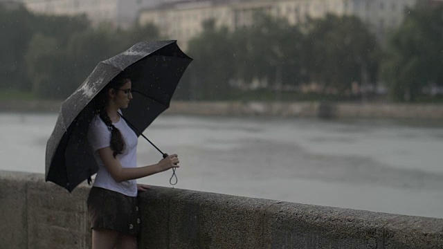 孤独的女孩撑着伞走在雨天的街道上，慢镜头视频素材