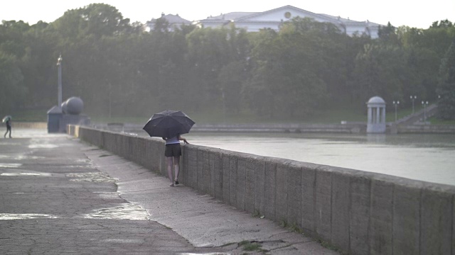 孤独的女孩撑着伞走在雨天的街道上，慢镜头视频素材