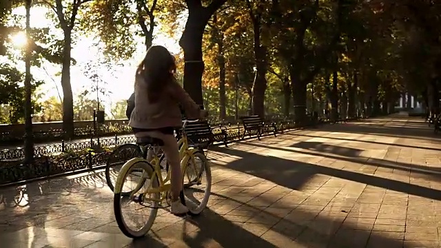 在夏天，一对年轻幸福的夫妇或朋友在空旷的城市公园或林荫大道上骑自行车。人、休闲、生活理念视频素材