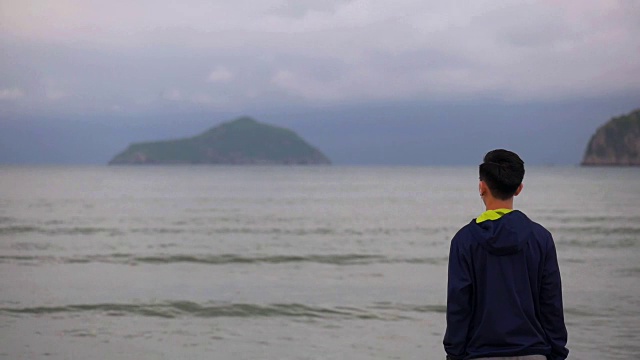 帅哥跑着站在沙滩上看海景，运动员在沙滩上伸展筋道。视频素材