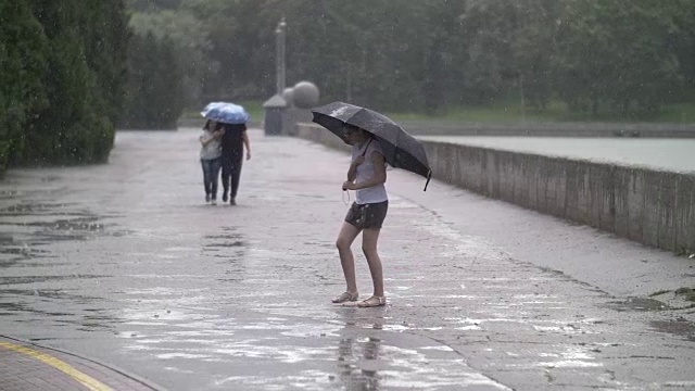 孤独的女孩在雨天撑着伞走在街上，在户外视频素材