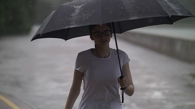 孤独的女孩在雨天撑着伞走在街上，在户外视频素材