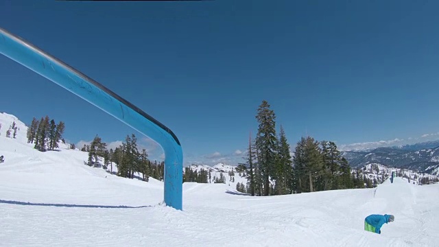 低角度:在一个风景优美的滑雪胜地，一名男性滑雪者从金属栏杆上滑下来。视频素材