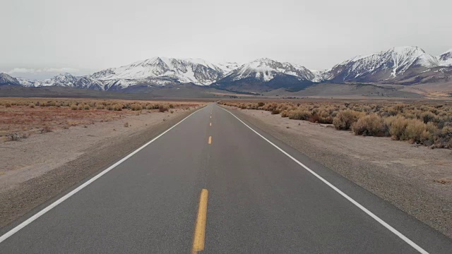 航拍:在空旷的高速公路上飞行，一览雪山美景。视频素材