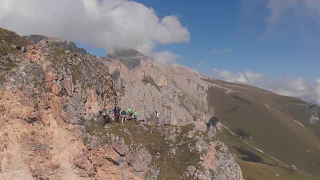 航拍一群在山顶拉绳子的登山者。视频素材