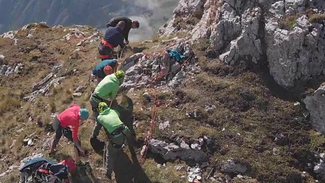 航拍一群在山顶拉绳子的登山者。视频素材