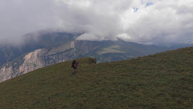 无人机拍摄到一名背着背包的游客爬上了山。视频素材