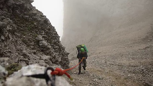 一个人拿着一根绳子爬山，慢动作。视频素材