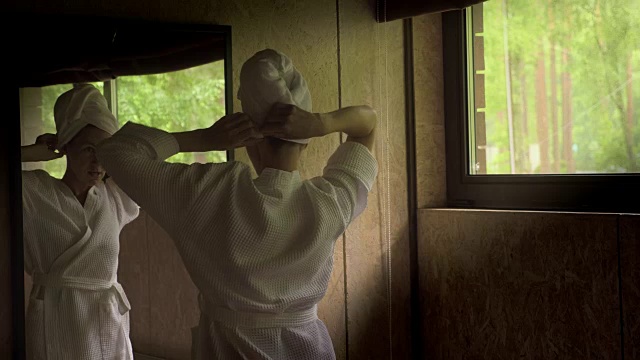 年轻迷人的女人站在浴室镜子前。视频素材