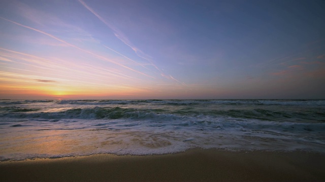 海上日出。海浪冲刷着海滩上的沙子。视频素材