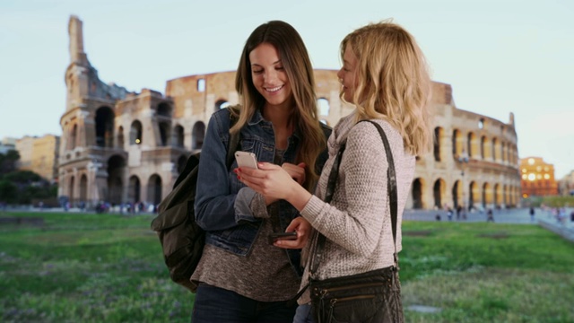 两位白人女性朋友在罗马斗兽场(Colosseum)附近漫不经心地使用智能手机视频素材