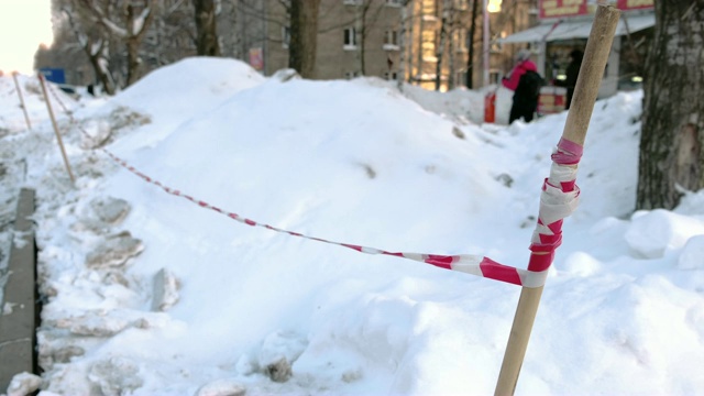 红色和白色警戒线在城市的路边。冬日和雪堆。视频素材