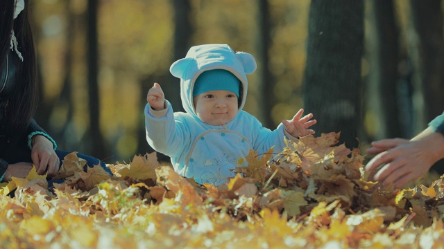 秋天公园里一个小孩的肖像。爸爸把秋天的落叶扔在森林里视频素材