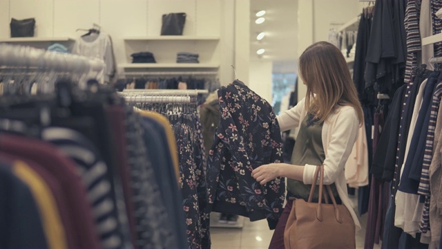 漂亮女人在服装店找衣服。视频素材