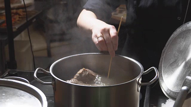 餐馆厨房里，金属锅里沸腾的肉汤。高清视频素材