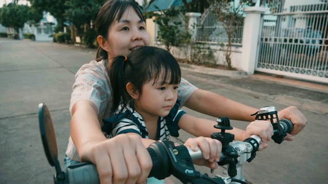 母亲和女儿在公路上骑车，一天在一个孩子的生活视频素材