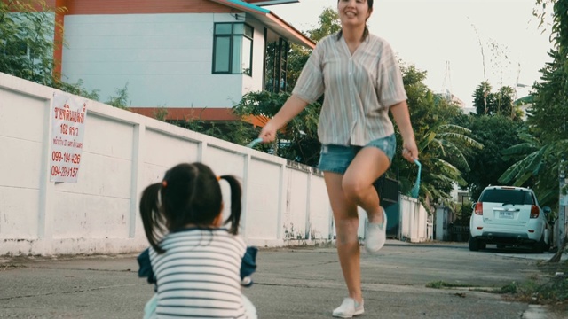 黄昏时分，小女孩看着妈妈跳绳视频素材