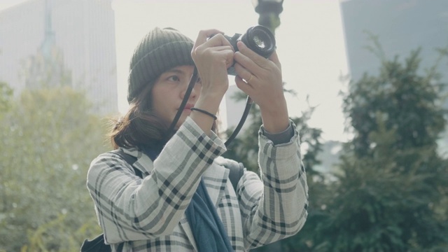 年轻的亚洲女子在中央公园用单反相机拍照。纽约视频素材