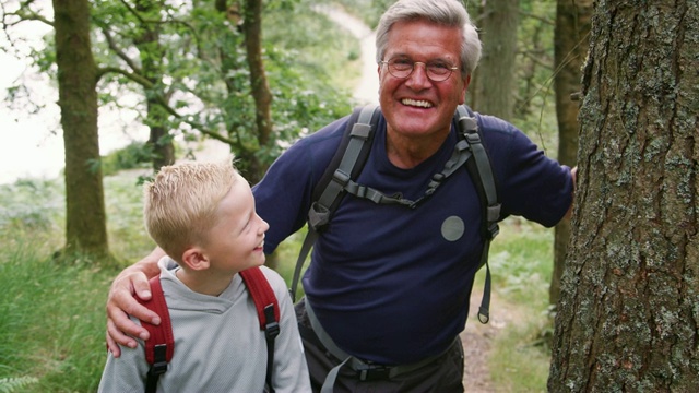 祖父和孙子在森林里徒步旅行时休息，英国湖区视频素材