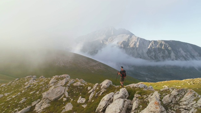 在日落时分，一名年轻人在意大利阿布鲁佐山的山脊边缘徒步旅行视频素材