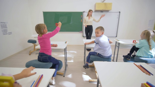 在学校的课桌上为可爱的小学生讲授认知课视频素材