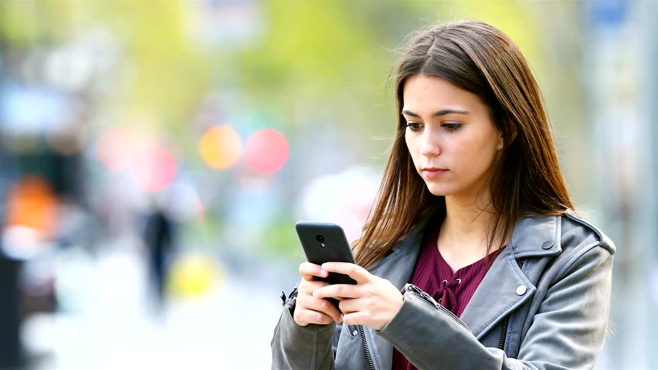 严重的青少年在户外用智能手机发短信视频素材