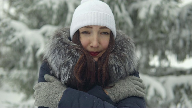 一个年轻女子在冬天的森林里散步时被冻僵了视频素材