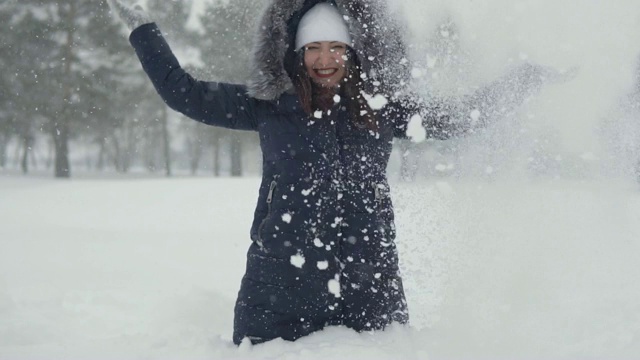 美丽的女人坐在雪堆里。在冬季公园里愉快地散步视频素材