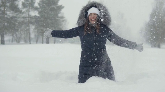 在冬季公园里愉快地散步。年轻女子在雪堆里玩雪视频素材