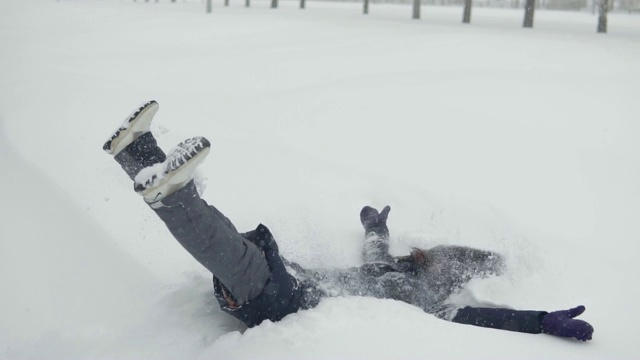 梅里在公园里散步。快乐的女人躺在雪地里视频素材