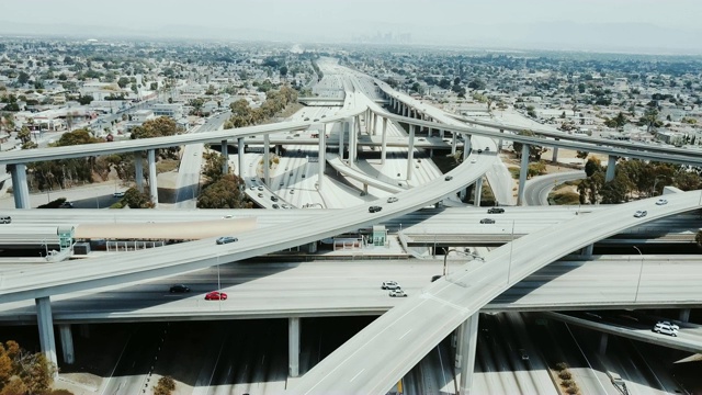 无人机在洛杉矶巨大的高速公路十字路口倒车，汽车通过许多路口和桥梁。视频素材