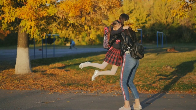 一个女人在学校见她的小女儿。妈妈让女儿绕着她转。夕阳下的慢动作视频素材