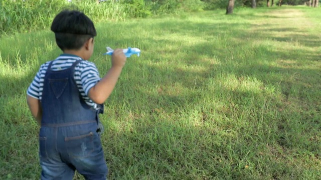 快乐时光，孩子在公园里玩飞机模型，概念孩子梦想，慢动作视频素材