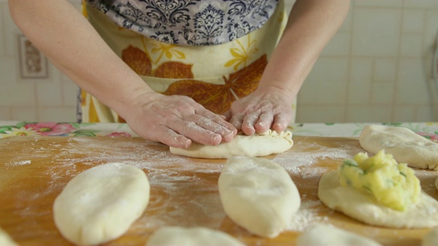 烹饪馅饼。女人把馅粘在面团里视频素材