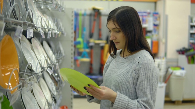 一位年轻女子在一家家居用品店里挑选盘子视频素材