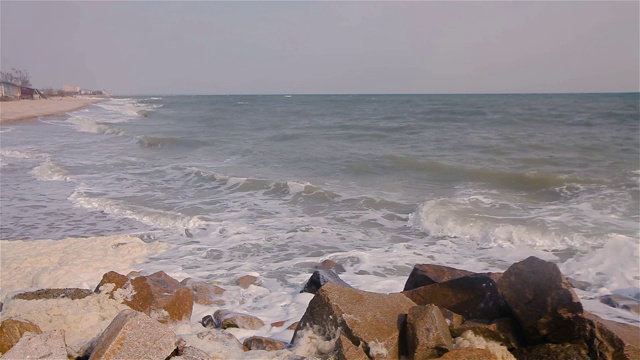 海浪拍打着海边的岩石，海浪沿着海岸翻滚，暴风雨前的天气视频素材