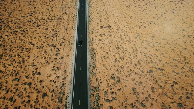 无人机跟随银色汽车行驶在干燥的美国沙漠景观公路，全球变暖和侵蚀的概念。视频素材