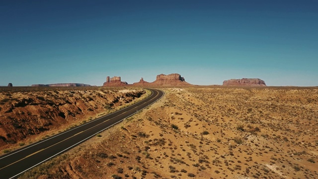 无人机飞行在空砂岩沙漠高速公路转弯在纪念碑谷，亚利桑那州史诗般平坦的山脉。视频素材