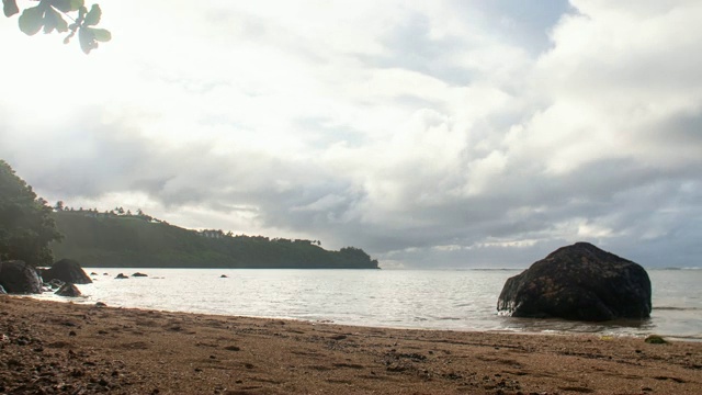 沙蟹在海滩上爬行，令人惊叹的日落背后的山脉运动，在夏威夷考艾岛水的时间推移岩石视频素材