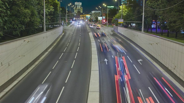 城市景观与光线从宽阔的城市街道上的交通在夜晚与建筑的背景视频素材