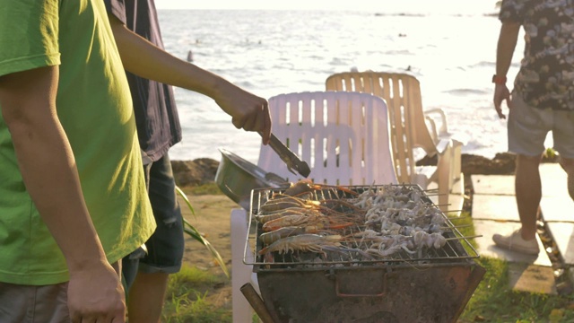 一群朋友在海滩上烧烤猪肉、虾和海鲜聚会活动视频素材