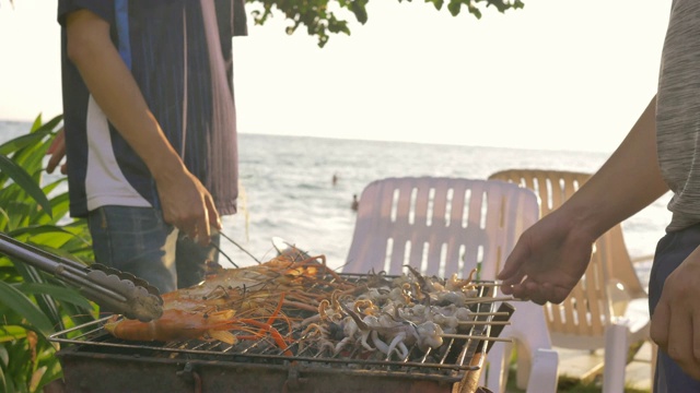 一群朋友在海滩上烧烤猪肉、虾和海鲜聚会活动视频素材