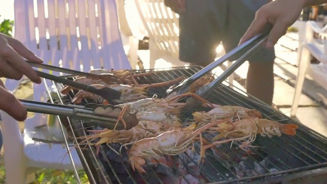 一群朋友在海滩上烧烤猪肉、虾和海鲜聚会活动视频素材